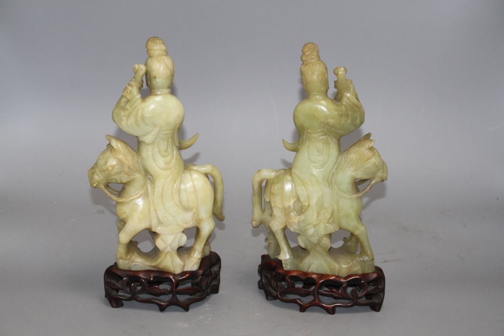 A pair of Chinese bowenite jade groups of a lady riding a horse, wood stands total height 26.5 and 27cm